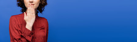 partial view of young woman in burgundy blouse showing symbol meaning thank you on sign language isolated on blue, bannerの写真素材