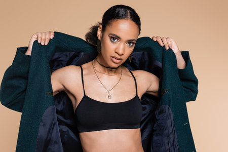 young african american model in crop top wearing dark blue oversized blazer isolated on beigeの写真素材