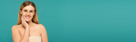 Positive young woman with freckles standing isolated on turquoise, banner