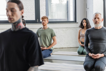 Interracial group of people meditating in Thunderbolt asana in yoga classの写真素材