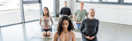 Multicultural people meditating in Thunderbolt asana on yoga mats in studio, bannerの写真素材