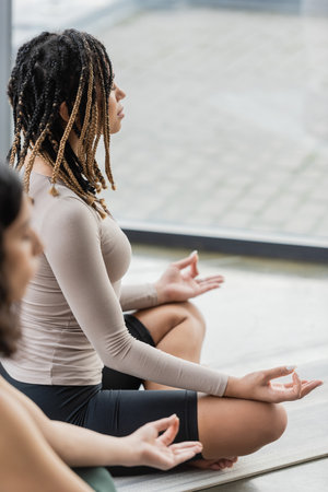 Side view of african american woman doing gyan mudra in yoga studioの写真素材