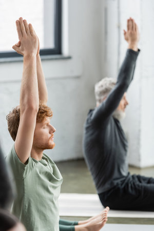 Young redhead man doing anjali mudra while sitting in yoga classの写真素材