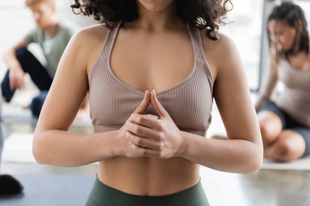 Cropped view of woman meditating near blurred people in yoga classの写真素材