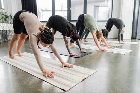 Young african american woman doing Downward Facing Dog asana in group in yoga classの写真素材
