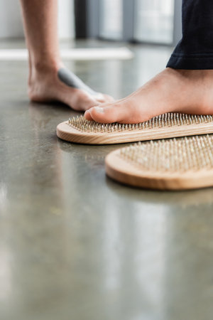 Cropped view of man practicing nail standing on sadhu board in yoga studioの写真素材