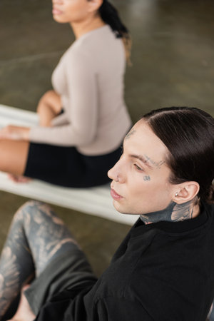 Young tattooed man in sportswear looking away in yoga classの写真素材