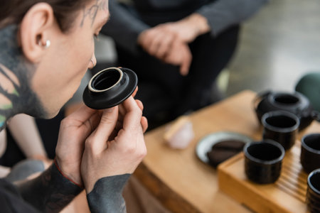 tattooed young man smelling puer tea near Chinese cups in yoga studioの写真素材