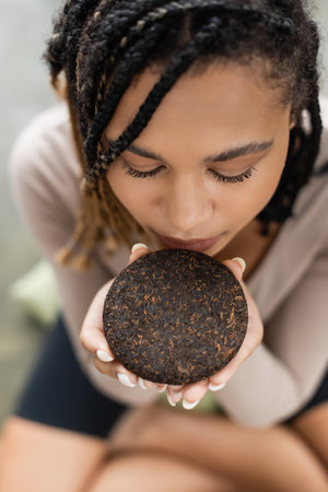 top view of african american woman with dreadlocks smelling compressed puer teaの写真素材