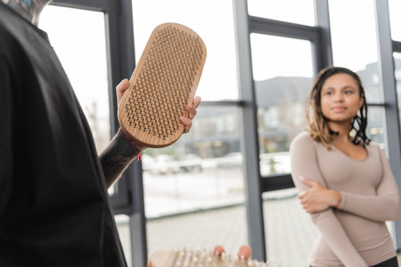 Tattooed man holding sadhu board near blurred african american woman in yoga studioの写真素材