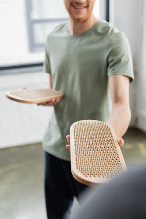 Cropped view of blurred smiling man holding sadhu board in yoga class