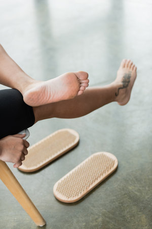 partial view of tattooed woman showing bare feet after nail standing practice in yoga studioの写真素材