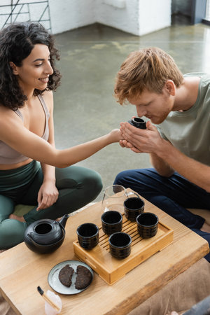 curly middle eastern woman smiling while giving to smell puer tea to redhead manの写真素材