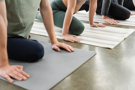 Cropped view of people doing Half Pigeon asana on mats in yoga classの写真素材