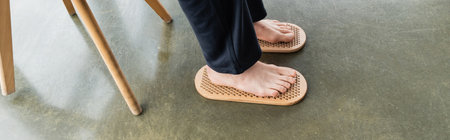 high angle view of man stepping with bare feet on sadhu board in yoga studio, bannerの写真素材