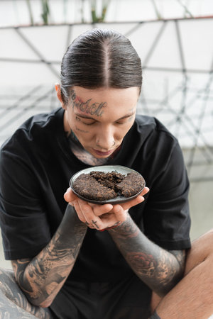 young man with tattoos smelling fermented tea leaves of puer in yoga studioの写真素材