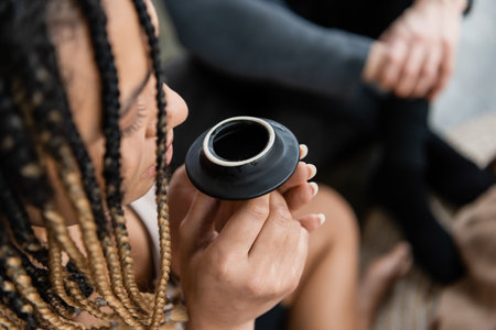 overhead view of african american woman with dreadlocks smelling puer tea from teapot lidの写真素材
