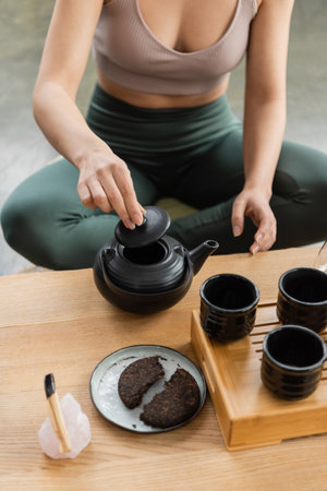 cropped view of woman in sportswear brewing puer tea in Chinese teapotの写真素材