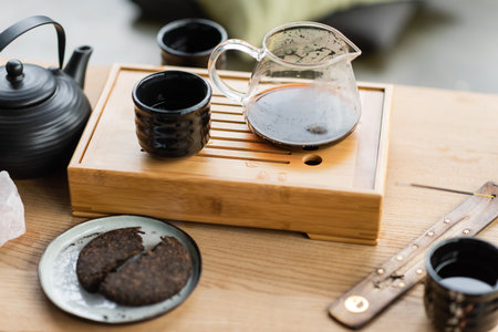 compressed pu-erh tea near Chinese teapot and incense stick on wooden standの写真素材