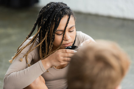 african american woman with dreadlocks drinking puer tea in yoga studioの写真素材