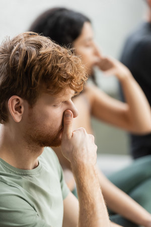 Redhead man practicing nostril breathing exercise in yoga studioの写真素材