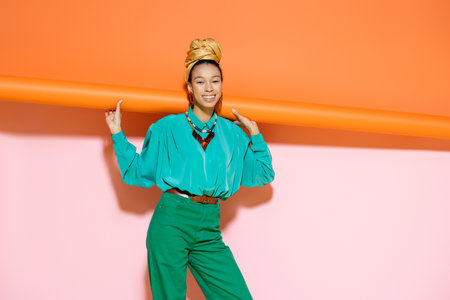 Smiling african american woman in bright outfit posing on colorful backgroundの写真素材