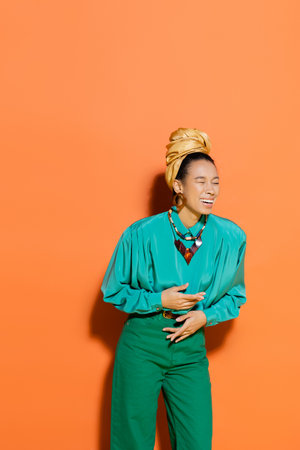 Stylish african american model laughing on orange backgroundの写真素材