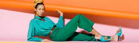 Stylish african american model in summer clothes and headscarf posing on colorful background, bannerの写真素材