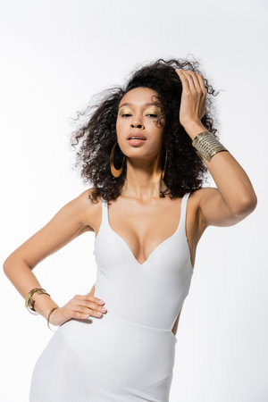 pretty african american woman in mini dress posing with hand on hip on greyの写真素材