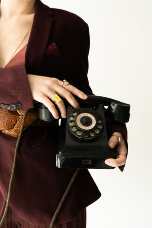 partial view of stylish woman in blazer and finger rings holding vintage telephone isolated on greyの写真素材