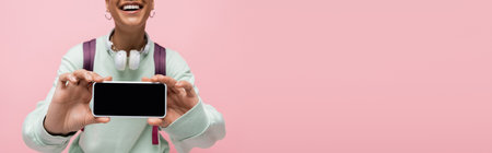 cropped view of cheerful african american woman holding smartphone with blank screen isolated on...