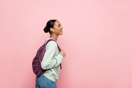 Positive african american student with backpack standing isolated on pinkの写真素材