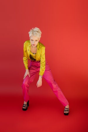 full length of young albino model in trendy outfit posing on carmine pink