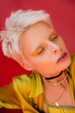 portrait of blonde albino woman with bright eyeliner and closed eyes on carmine pinkの写真素材