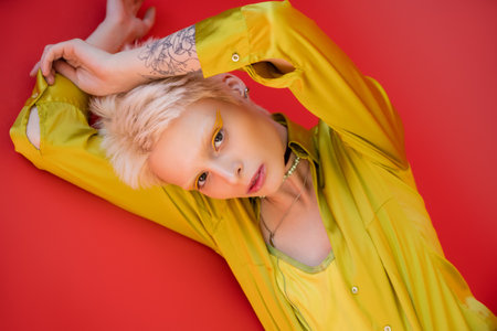 portrait of blonde woman with tattoo looking at camera on carmine pink