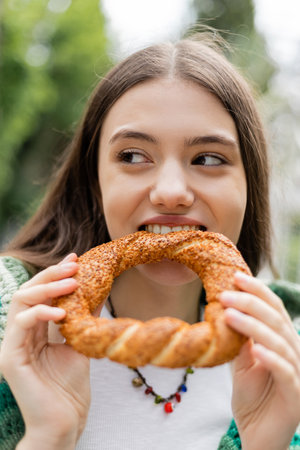 Young woman biting turkish simit bread outdoors in Istanbulの写真素材
