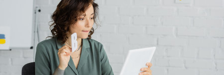 Speech therapist holding letter during online lesson on digital tablet in consulting room, banner
