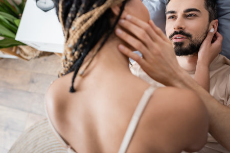 high angle view of bearded man looking at sexy african american woman on blurred foreground at homeの写真素材