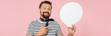 happy french guy in striped t-shirt and neck scarf holding speech bubble isolated on pink, bannerの写真素材