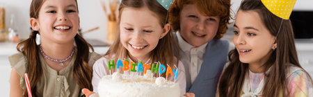 happy birthday girl holding cake with candles near cheerful friends during celebration at home,...