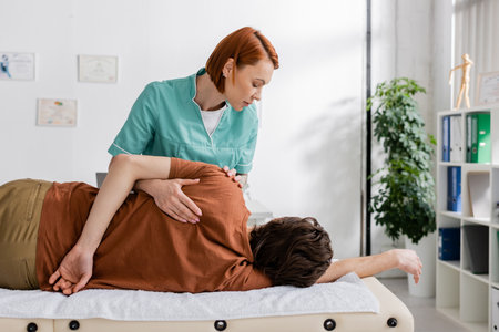 osteopath making shoulder massage to injured man during rehabilitation treatmentの写真素材