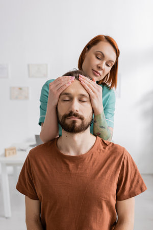 physiotherapist examining injured bearded man in consulting roomの写真素材