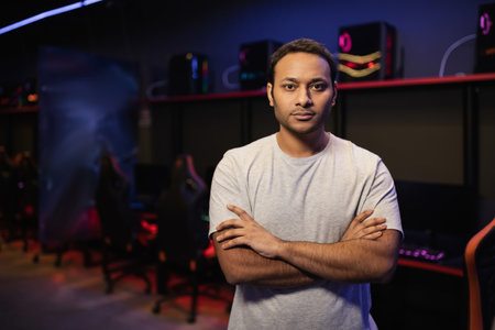 Indian gamer crossing arms and looking at camera in gaming club