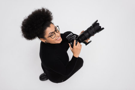 top view of overjoyed african american content producer in eyeglasses holding professional digital...