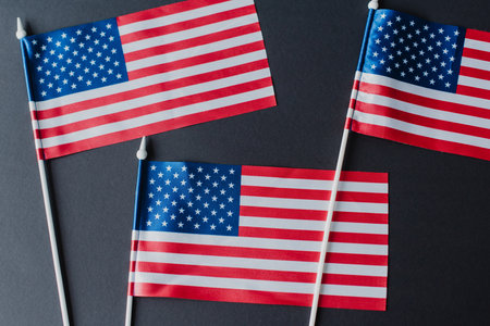 top view of three American flags with stars and stripes isolated on black