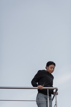 Sad multiracial woman with depression standing near railing outdoorsの写真素材