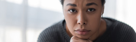 Young multiracial woman with depression looking at camera at home, bannerの写真素材