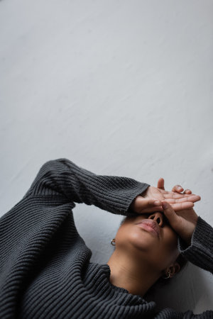 Low angle view of multiracial woman with depression leaning on wall at homeの写真素材