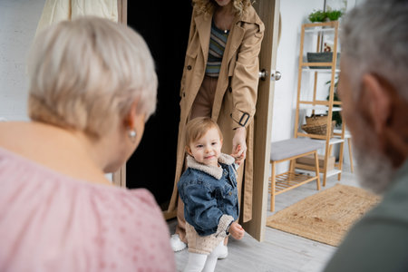 blurred middle aged couple meeting daughter with little child at homeの写真素材
