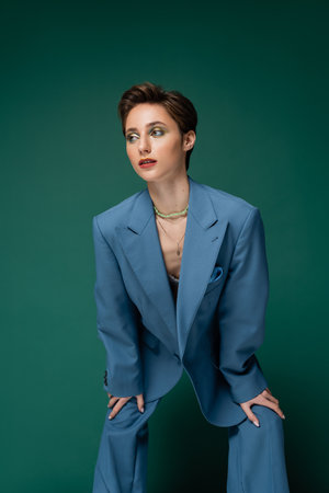 young well dressed model with short hair posing in blue suit on turquoise backgroundの写真素材